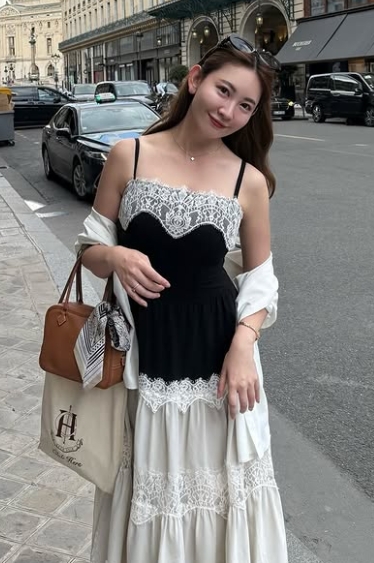 パリの街中の歩道でサングラスを頭にかけて一人で立っている小嶋陽菜の姿を撮った写真