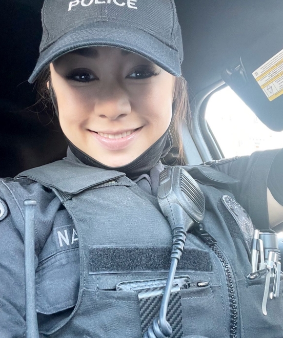 警察官の姿をして、キャップを被り、車内で笑顔で撮影されている警察官ゆりの写真