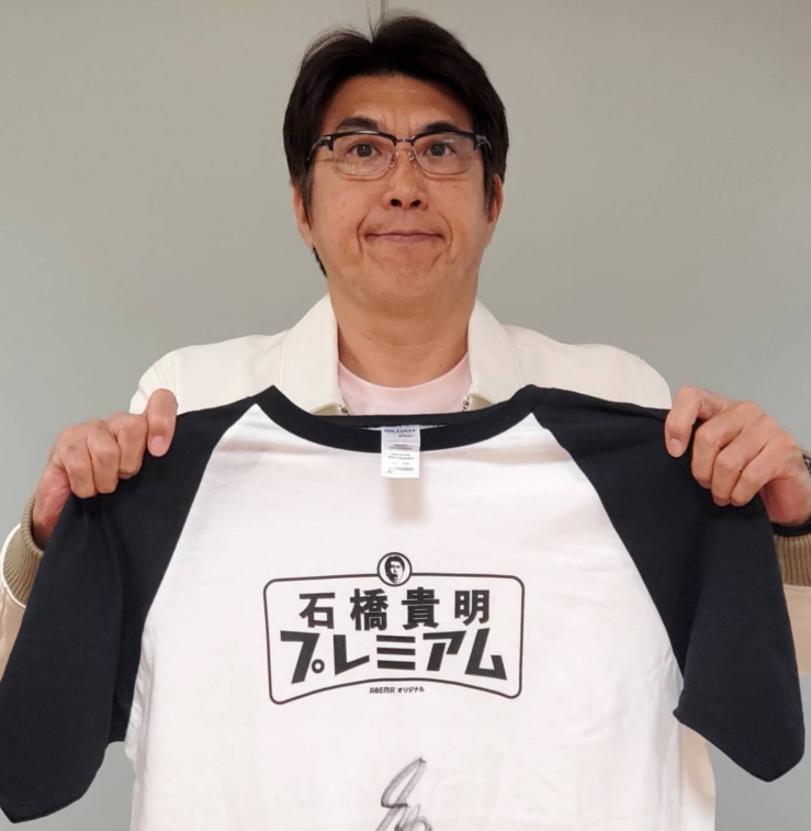 石橋貴明プレミアムのロゴ入りTシャツを宣伝している石橋貴明さん