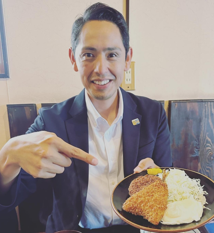 定食屋さんで注文をしたミックスフライ定食に指を指すポーズで写っている深作ヘスス
