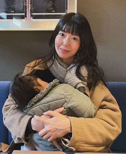 寝ているわが子を抱いて座っている石橋穂乃香