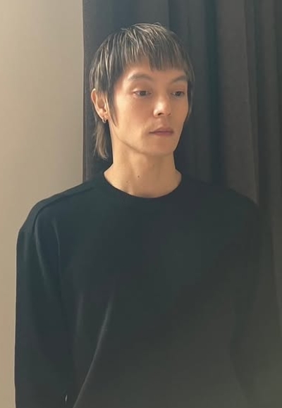 濃い茶色のカーテンの前で黒いトレーナーを着て写っている窪田正孝