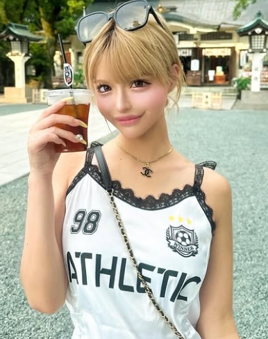神社の前で頭にサングラスをかけて、ドリンクを片手に顔の近くにして持っている
金髪でキャミソール姿の今井アンジェリカ