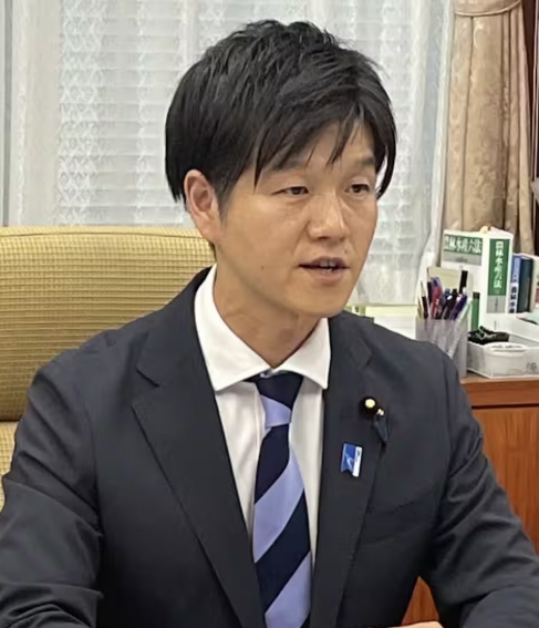 黒のスーツ姿でインタビューに答えている鈴木憲和農水大臣