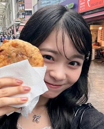 お菓子を持って写真を撮る林芽亜里
