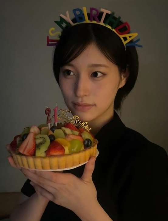 My BIRTHDAYのカチューシャを被りバースデーケケーキのフルーツタルトケーキを顔に近づけて写る黎架