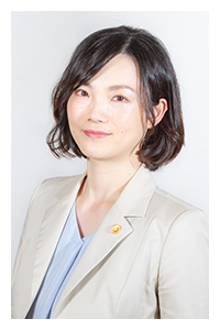 鈴木憲和さんの妻の坂栄鷹子さんの画像で、ベージュのジャケットに薄いブルーのブラウス姿で、髪型はショートヘアーの坂栄鷹子さんの画像。