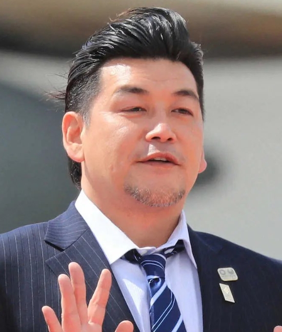 スーツ姿で手を挙げるサンドウィッチマン富澤たけしさん